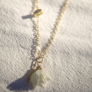 Gold necklace with a cross pendant on a textured white surface
