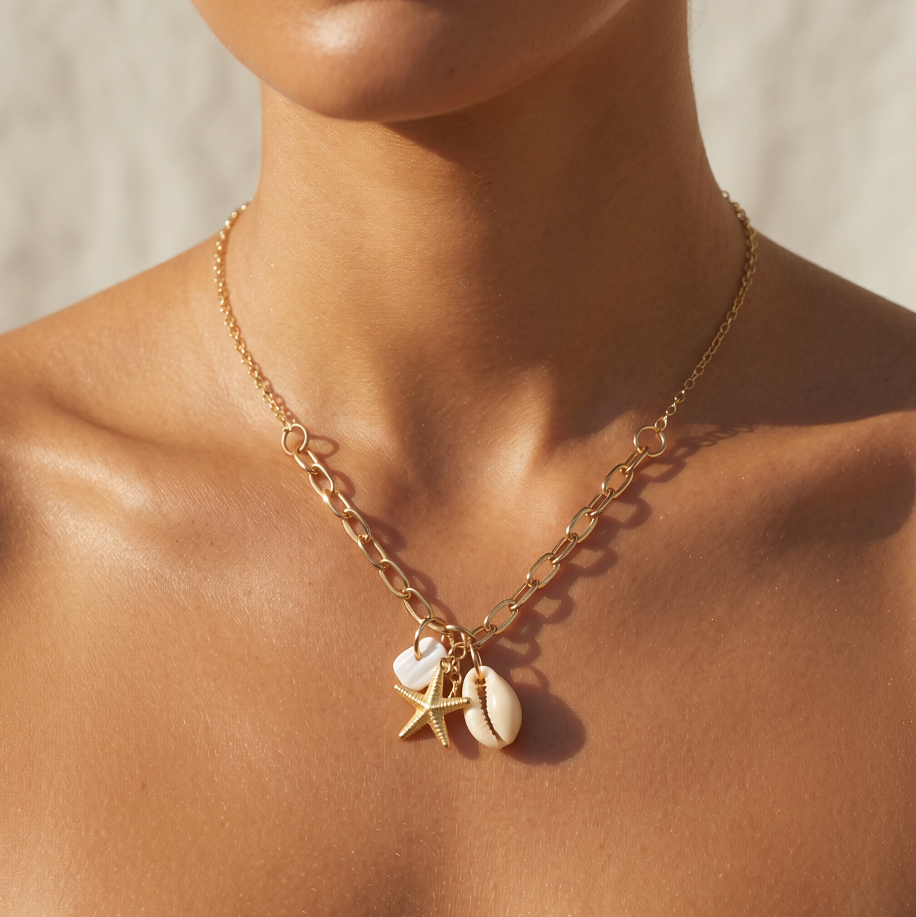 Gold chain necklace with starfish and shell charms on a person's neck against a neutral background